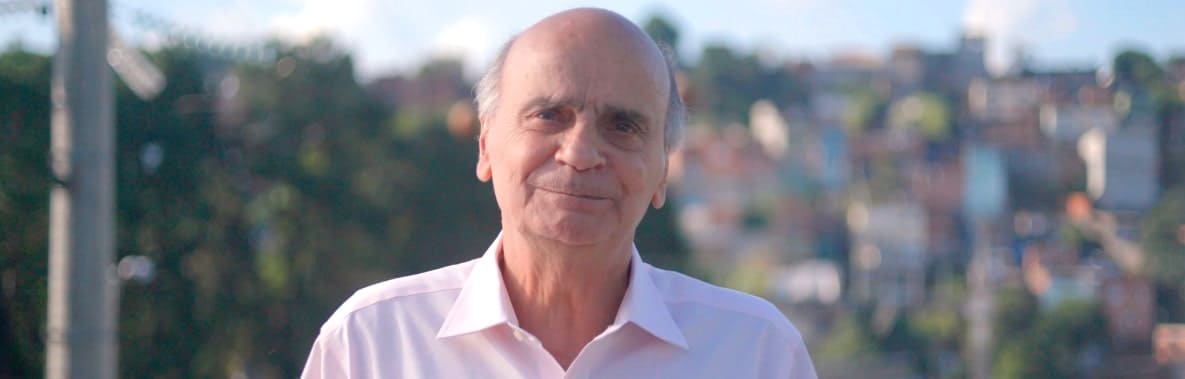 um menino olha para o lado, no colo de uma mulher