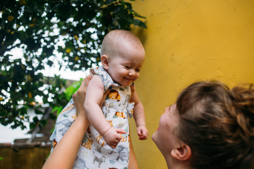 Uma mulher ergue uma criança para cima, que sorri com os olhos fechados. A imagem ilustra a matéria "Educação infantil no PNE: Fundação analisa Plano Nacional de Educação e sugere estratégias para alcançar metas de creches e pré-escolas".