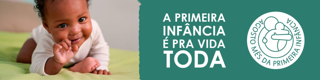 Bebê negro deitado de bruços sobre uma cama com lençol verde-claro, olhando para a câmera com expressão alegre e curiosa. Ao lado, sobre fundo verde escuro, está escrito em letras brancas: "A primeira infância é pra vida toda". Abaixo do texto, há o selo oficial do Mês da Primeira Infância com o desenho de um adulto segurando uma criança no colo e a inscrição "Agosto – Mês da Primeira Infância".