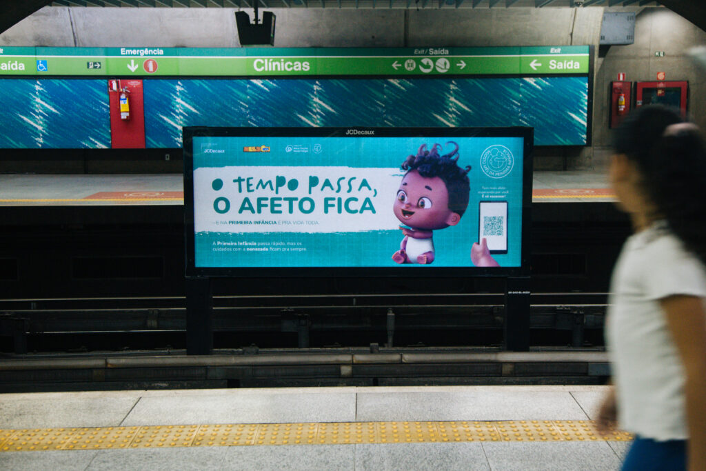 Nelson, o Nenê, é um personagem 3D de um bebê de dois anos, negro, cabelos cacheados e sorridente. Ele aparece em um painel horizontal de publicidade digital na estação Clínicas do metrô de São Paulo. Há a inscrição "o tempo passa, o afeto fica" em destaque.