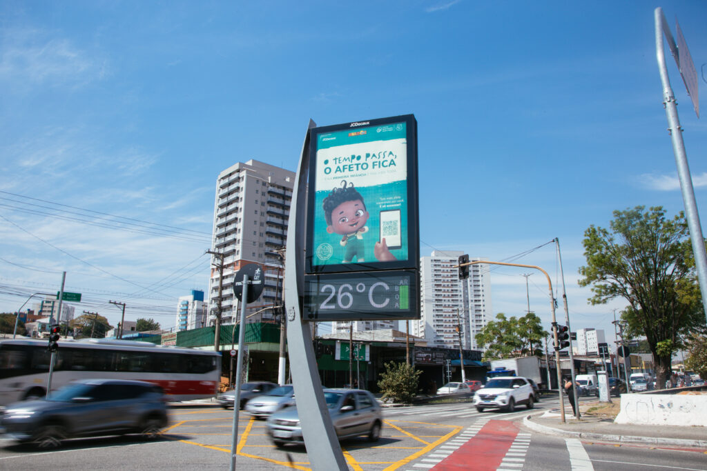 Nelson, o Nenê, em painel vertical de publicidade digital. Nelson é um personagem 3D, negro, de dois anos de idade que sorri. Em destaque os dizeres "O tempo passa, o afeto fica"