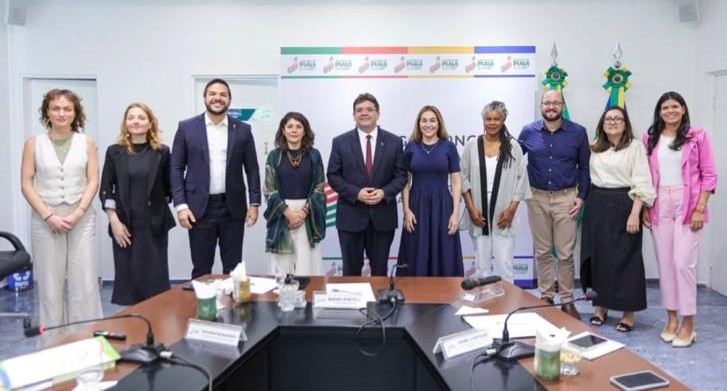 Grupo de homens e mulheres reunidos ao redor de uma mesa.