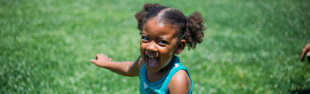 uma menina negra sorri em um gramado. ilustra matéria sobre vencedores do good start challenge 2025