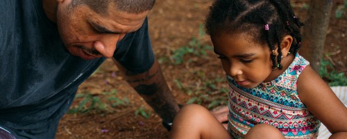 Pai e filha estão sentados na terra