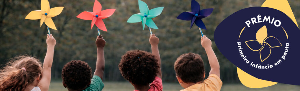 quatro crianças levantam cataventos. ao lado, um selo com a inscrição "prêmio primeira infância em pauta"